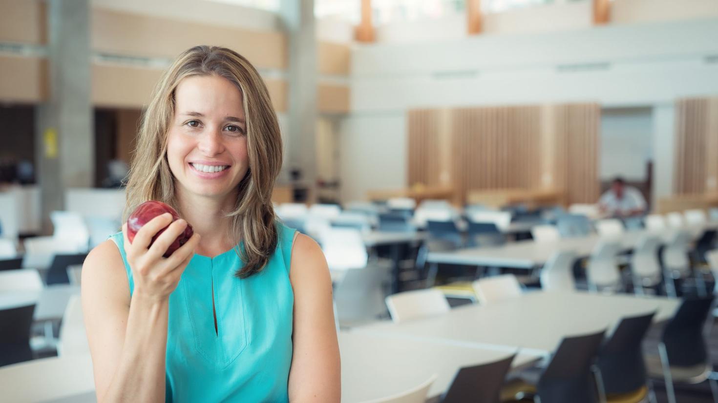 woman sin a conference room smiling and holding an apple