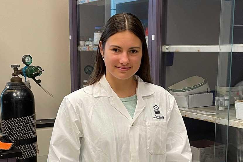 Mila standing in a lab wearing a lab coat
