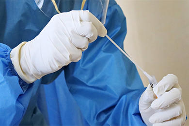Lab technician inserting a swab into a COVID-19 PCR test tube