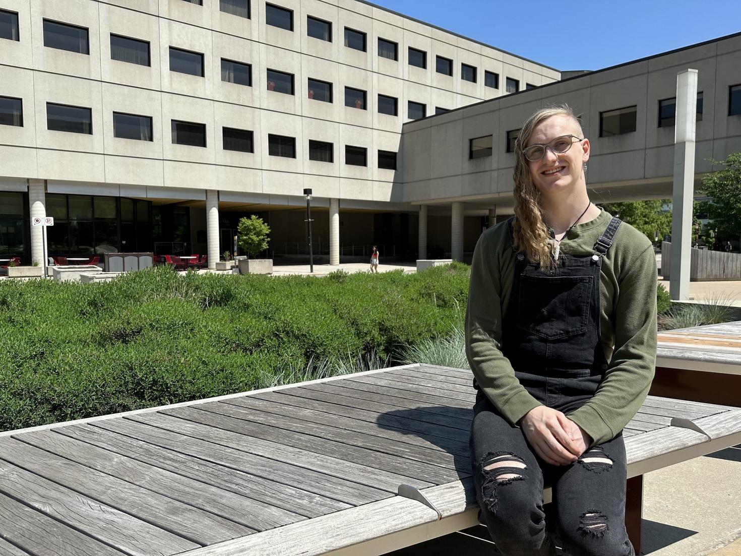 Zachary Wynen assis sur un banc devant l'édifice Lamoureux