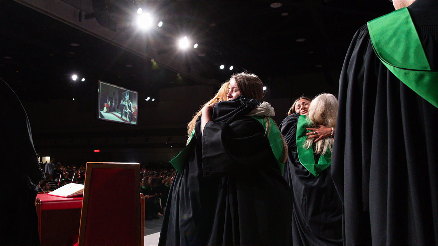 Deux diplômés sur scène s'étreignent pour fêter leur diplôme.