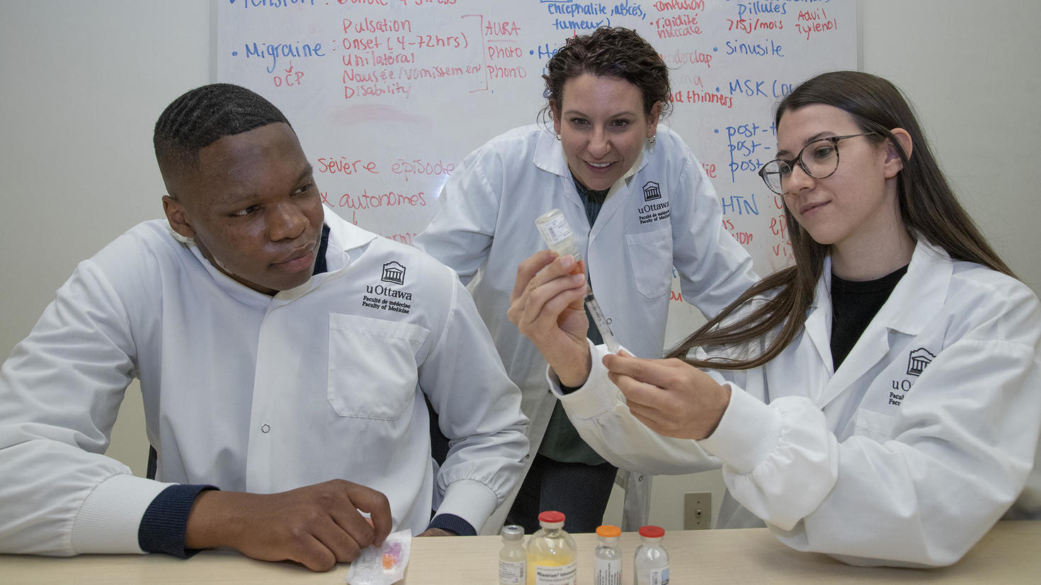 Une professeure assiste deux étudiants en phar