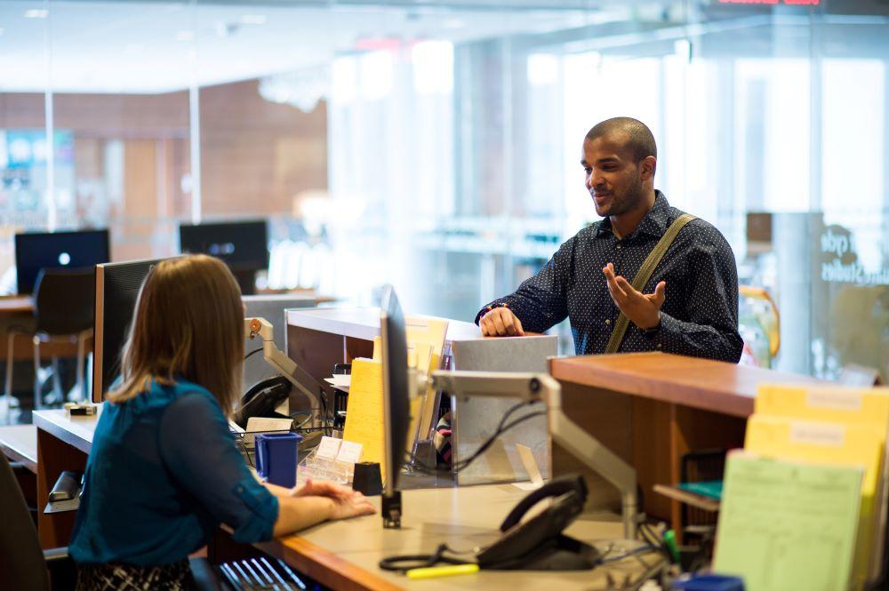 Person speaking to a customer service representative at a desk