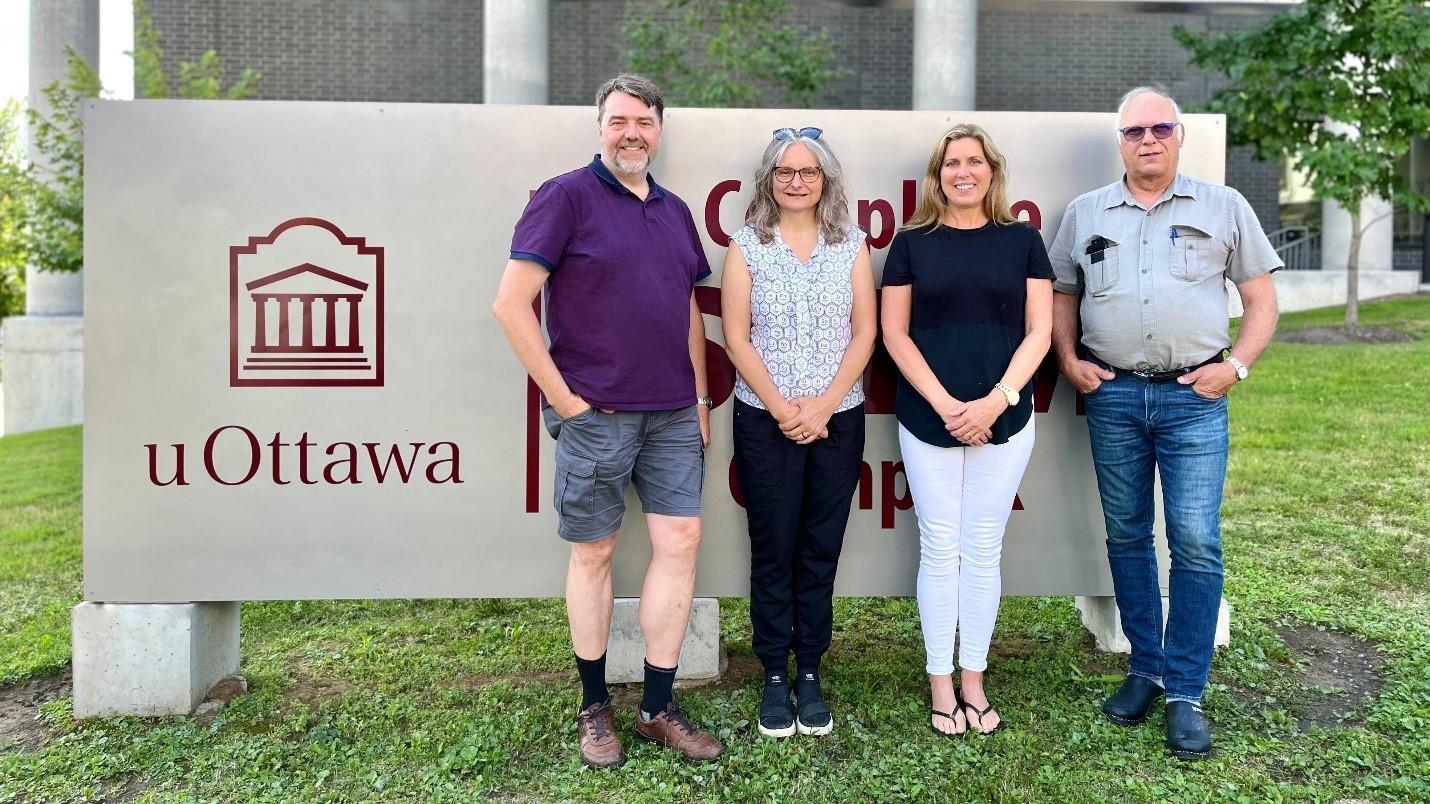 Professor Paul Mayer, Dr. Sharon Curtis, Deborah Quail-Blier, and Dr. Alexander Mommers, standing side by side in front of the uOttawa STEM complex sign. 