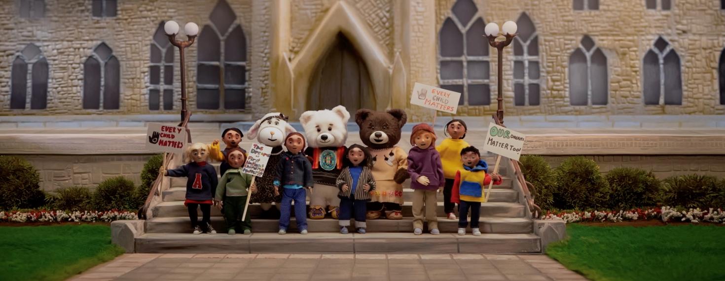 Groupe d'enfants et d'animaux en peluche sur les marches de la Colline du Parlement.
