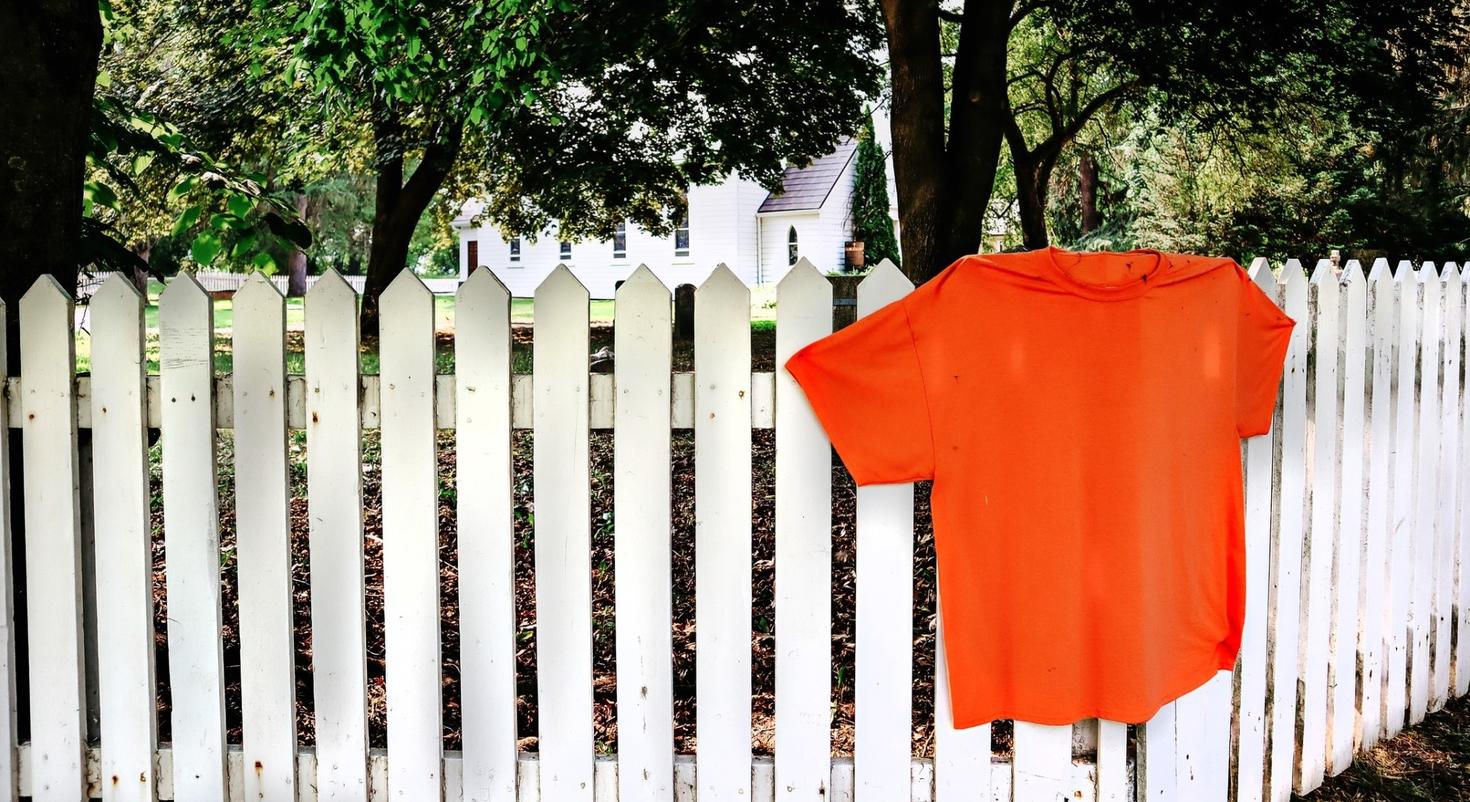 Orange shirt on a white fence