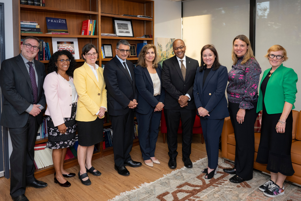 A group of people stand in a semi-circle, looking at the camera