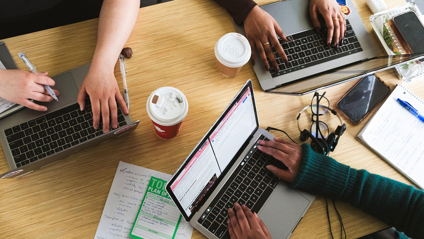 Étudiants à un bureau travaillant ensemble sur des ordinateurs portables avec du café.