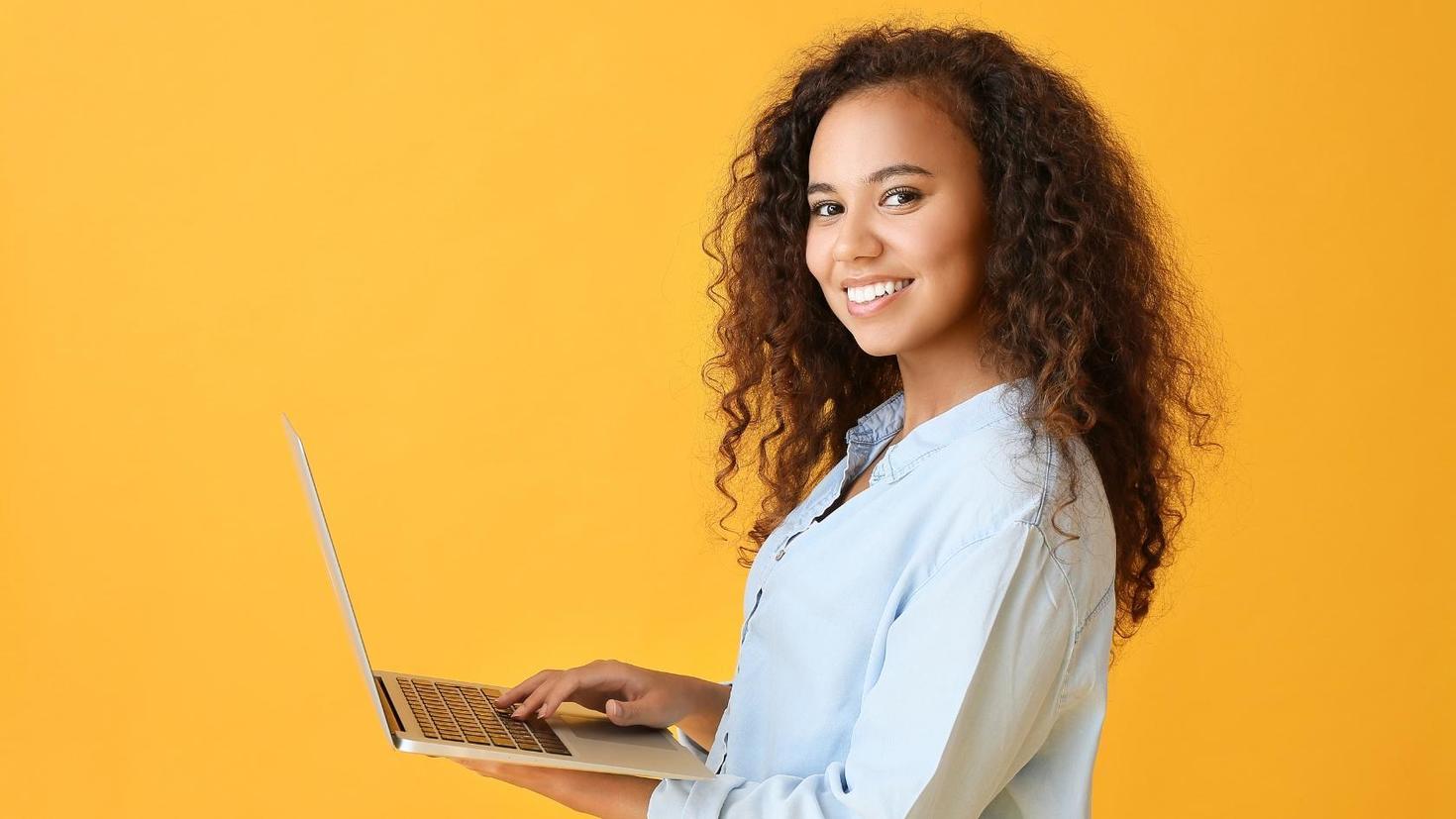 A smiling student holding a laptop