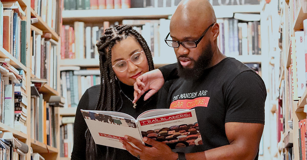 authors reading the trailblazers book they created in a library setting