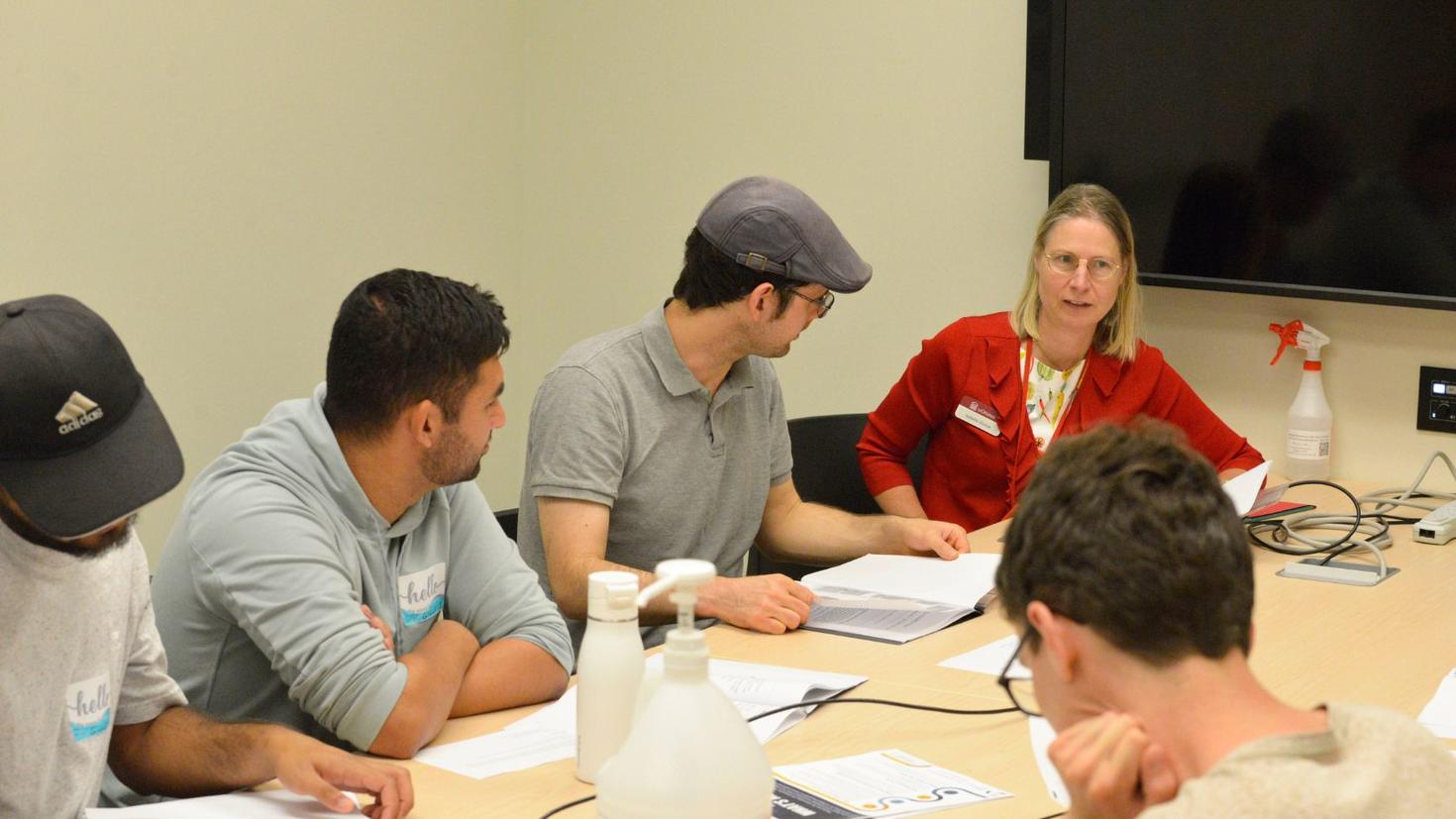 Group of students working together at a table with a teacher.