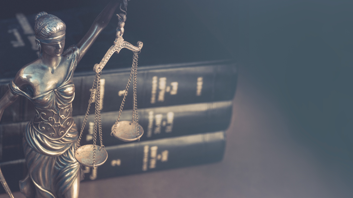 statue of a woman, blindfolded and holding the scales of justice in front of a stack of books