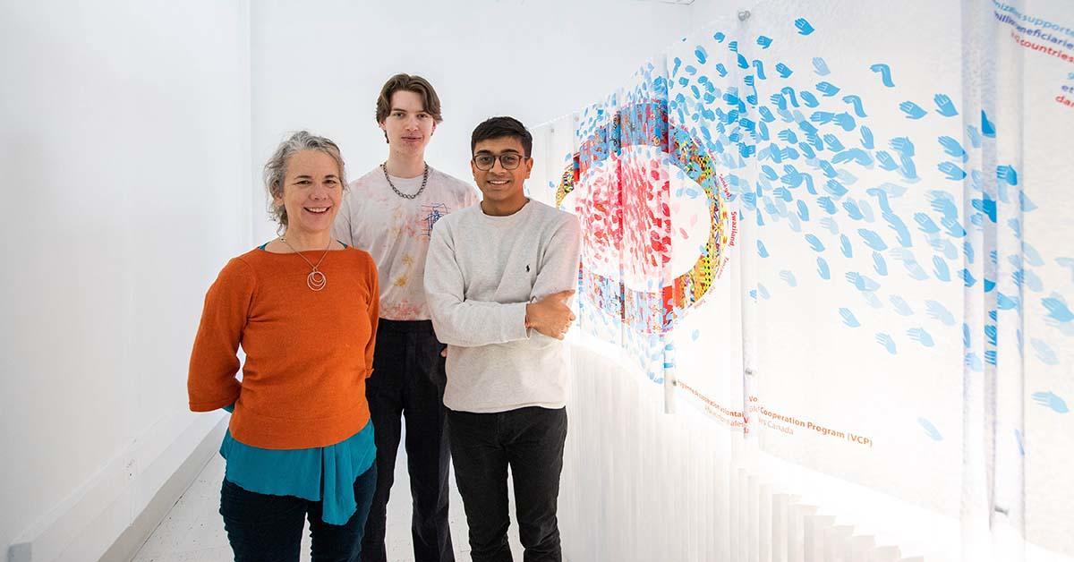 Jennifer Macklem, Willem Deisinger, and Devansh Shah standing beside their art installation