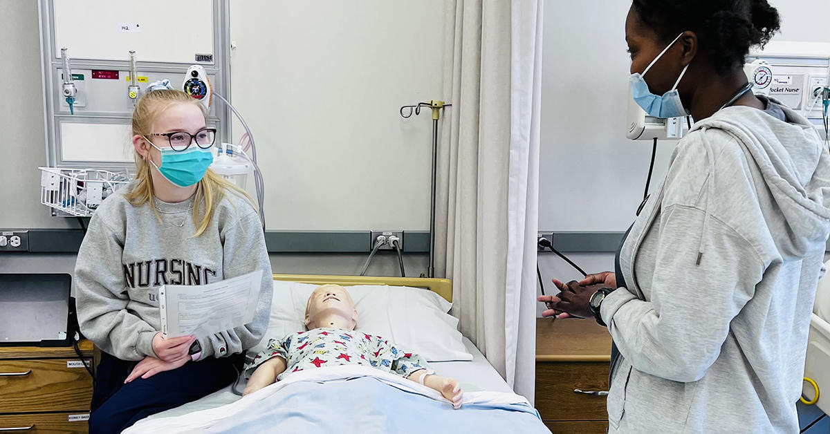 two nursing students talking to each other in the lab