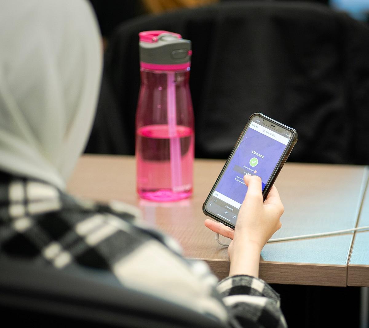 Girl in hijab holding cell phone in classroom