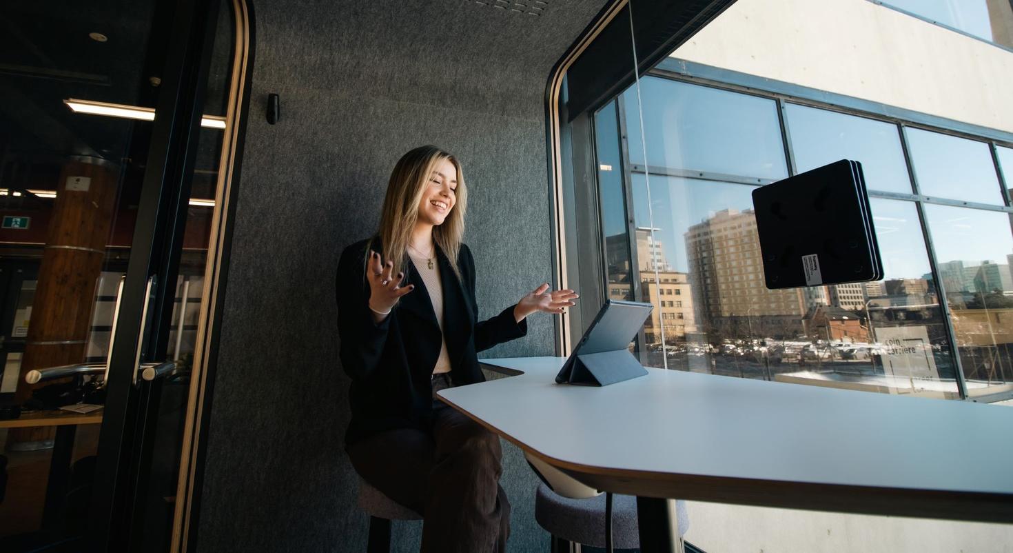 A woman looks at a computer screen in front of a window.