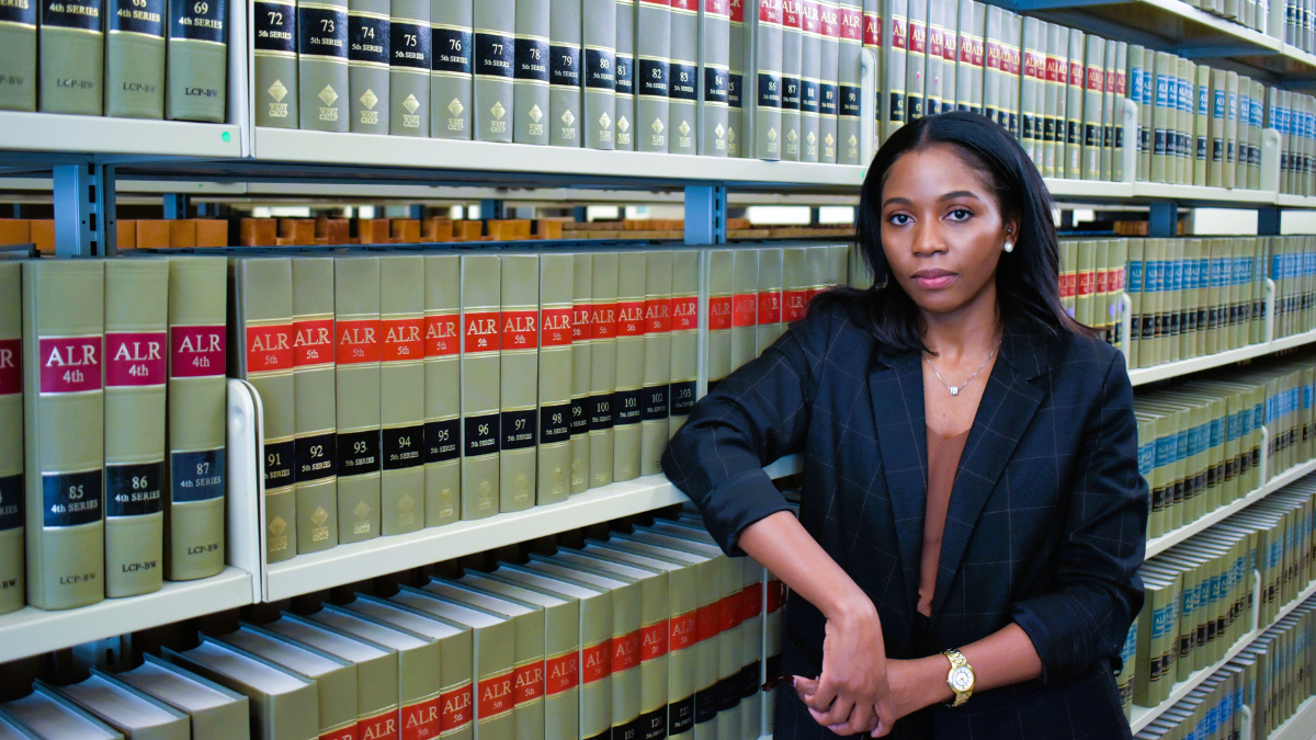 A woman stands in front of shelves of legal books in a library