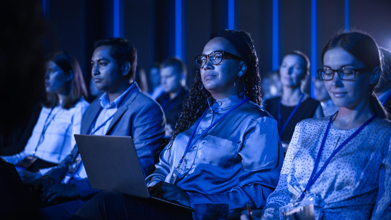 Members of an audience watch a show in a darkened theatre.