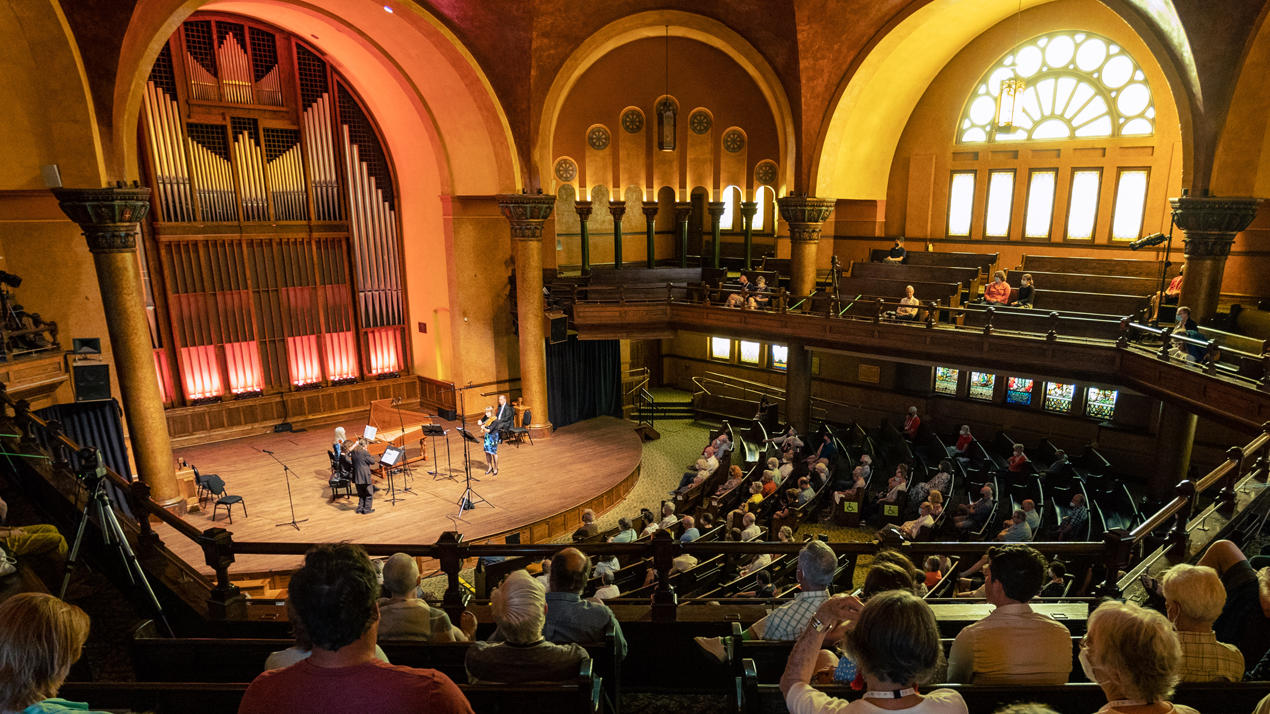 An audience inside a church watches a chamber orchestra.