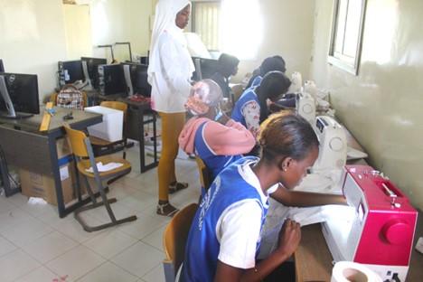 A group of 5 black women sitting on individual chairs while sewing