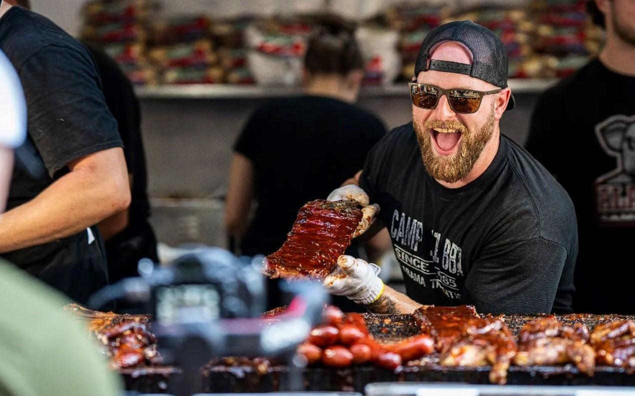 A grill master serves a rack of saucy ribs.