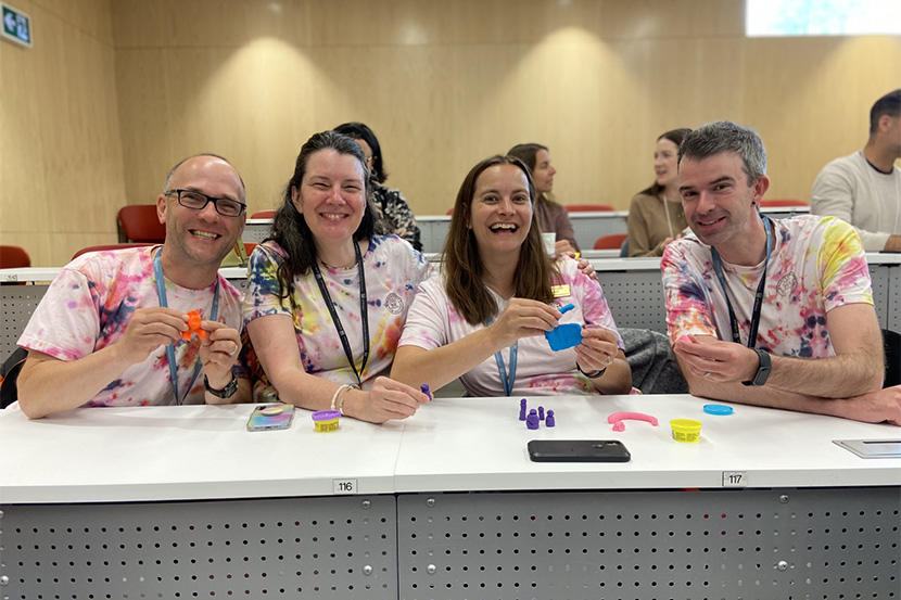 Des enseignants et enseignantes souriants, portant des chemises à cravate et tenant de la pâte à modeler. 