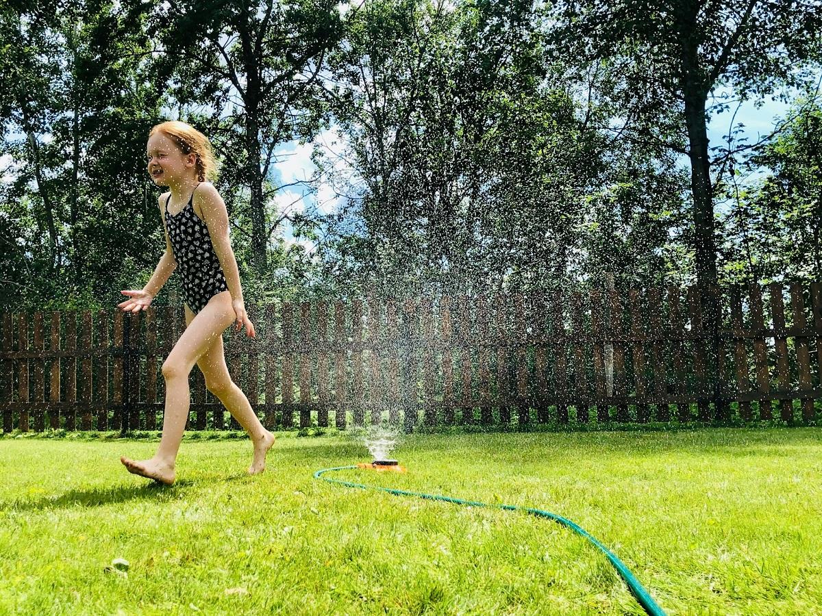 Girl running across a sprinkler