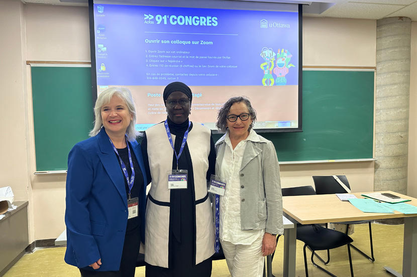 Three people standing in front of a screen in a classroom.