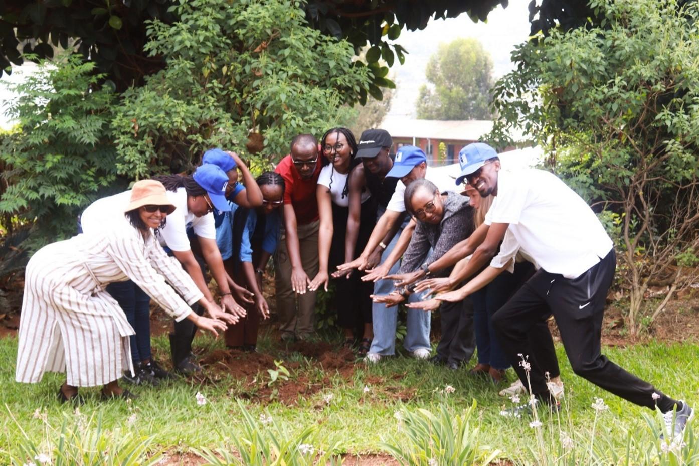 Photo of a group of 10 people lined up in a small garden from left to right. Each of them is bent over and has extended both hands towards the ground.