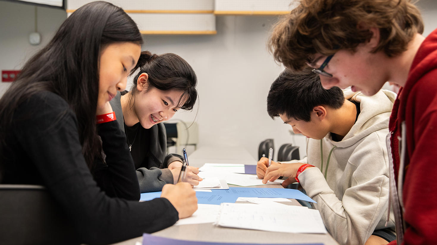Four participants (two boys and two girls) sit at a table solving a math problem at the 2024 uOttawa Math Camp.