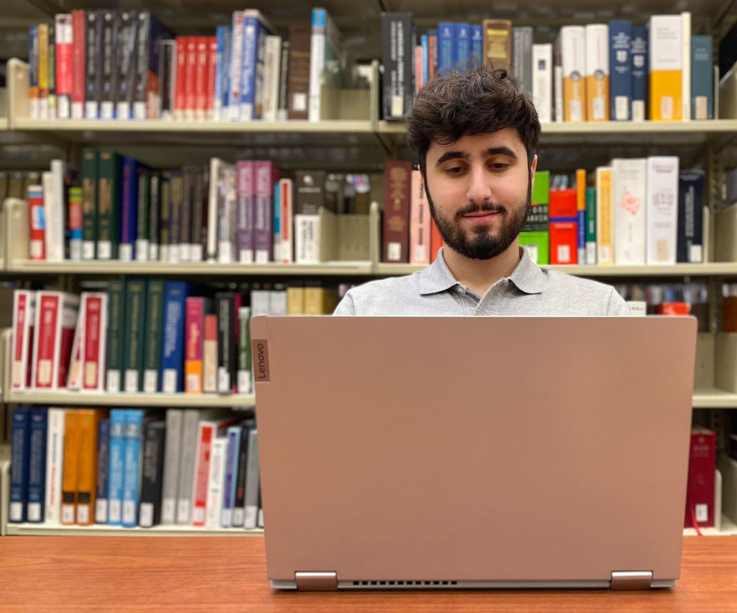 A person working on a computer in front of shelves full of books
