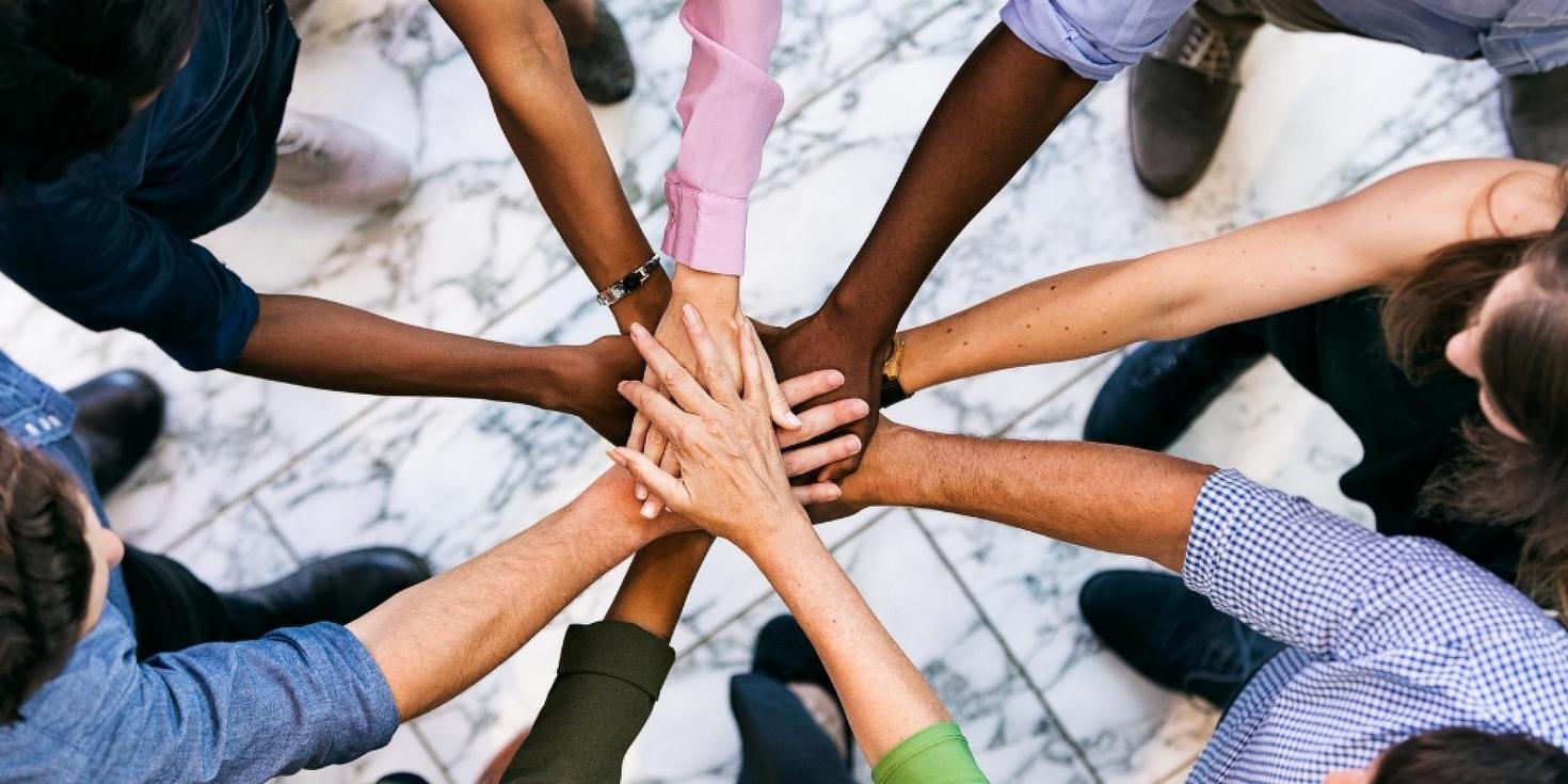Top view of people putting their hands in the centre of a circle 