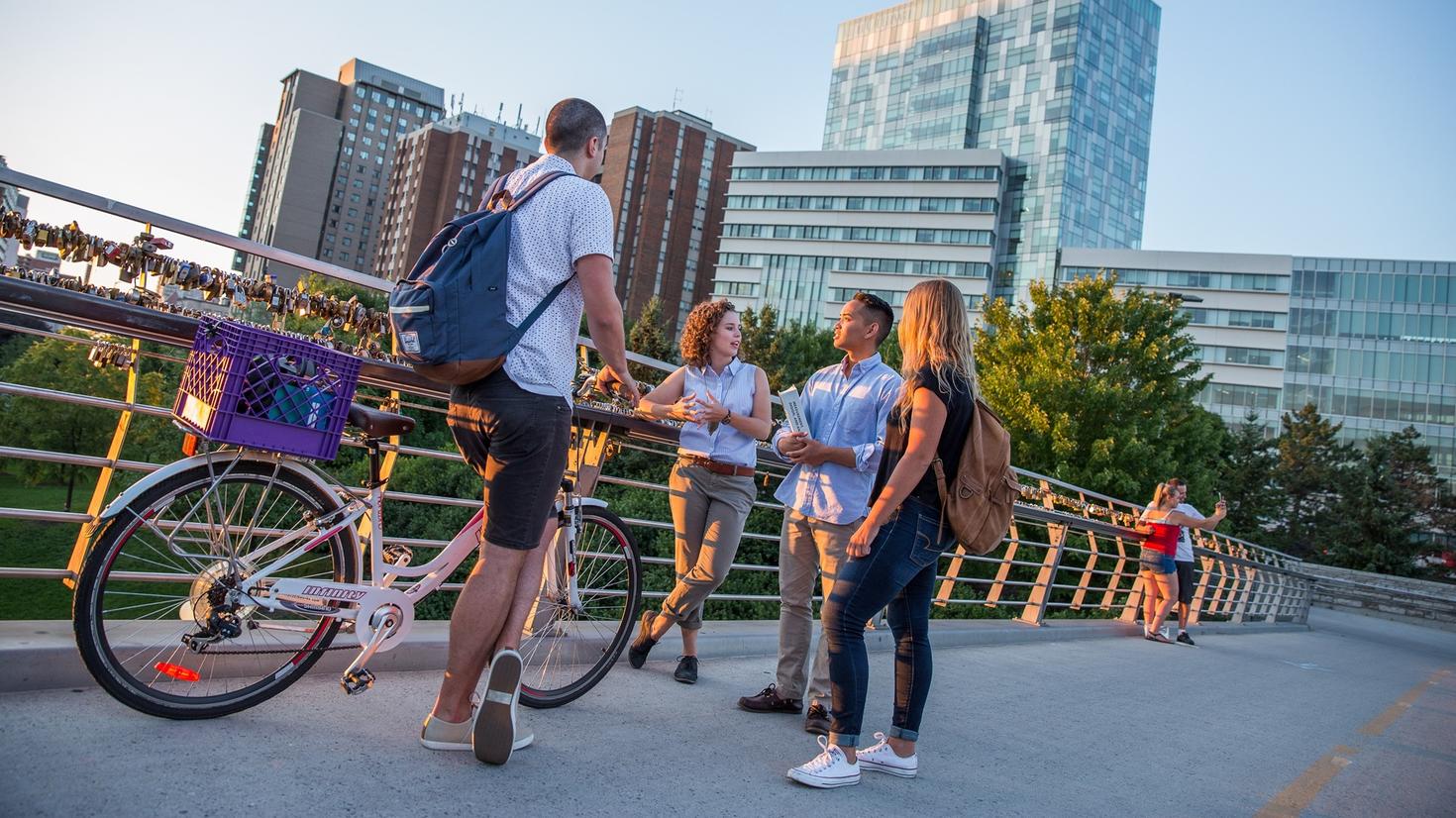 Group talking on bridge, one person with a bicycle.