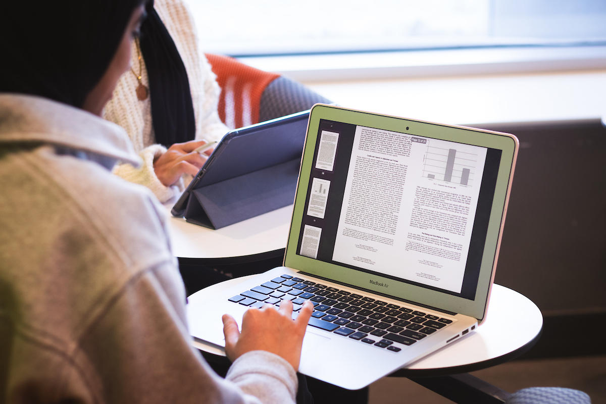 a student writing and using a laptop