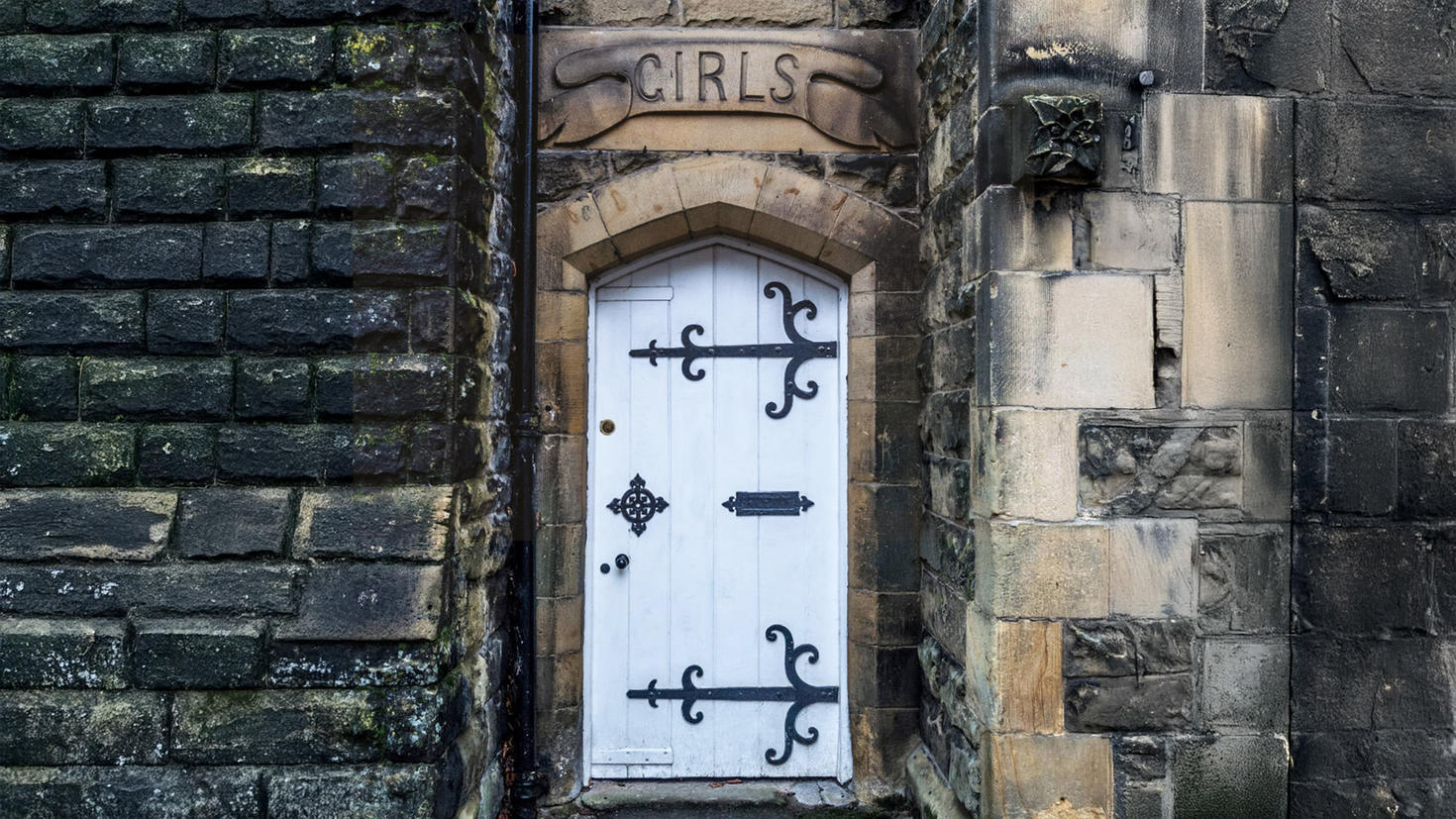 Le mot « Girls » est gravé au-dessus d'une vieille porte à l'entrée d'un bâtiment en pierre.