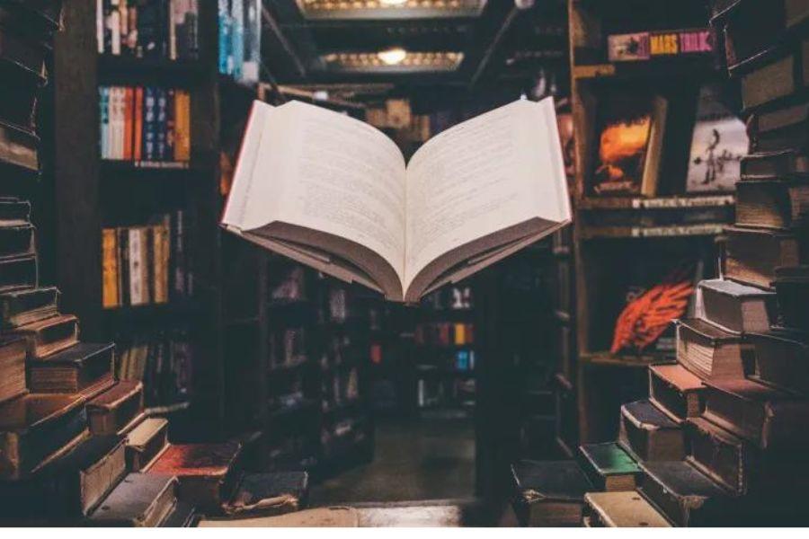 An open book surrounded by bookshelves. 