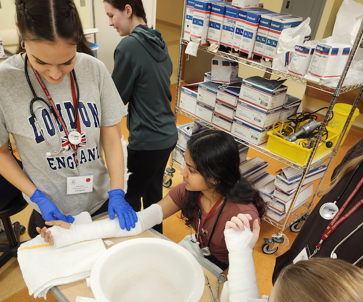 A student applying a cast to another student's arm