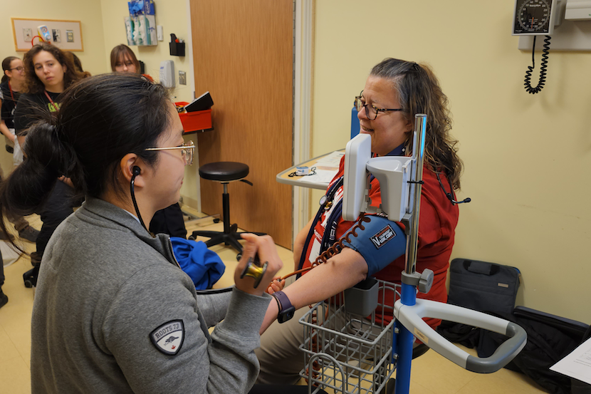 A student takes the blood pressure of a volunteer patient.
