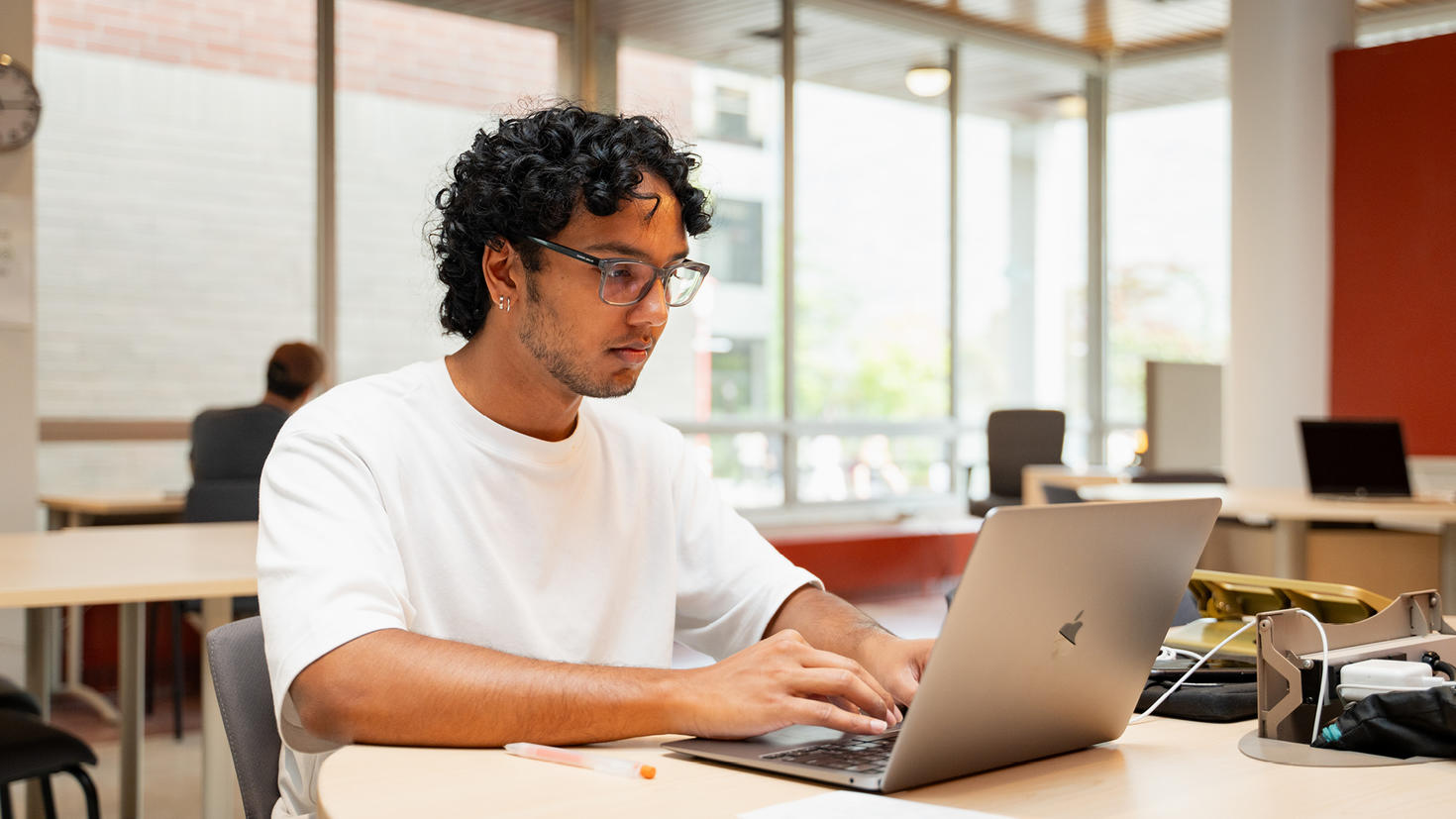 A student sits at a table studying with a laptop.