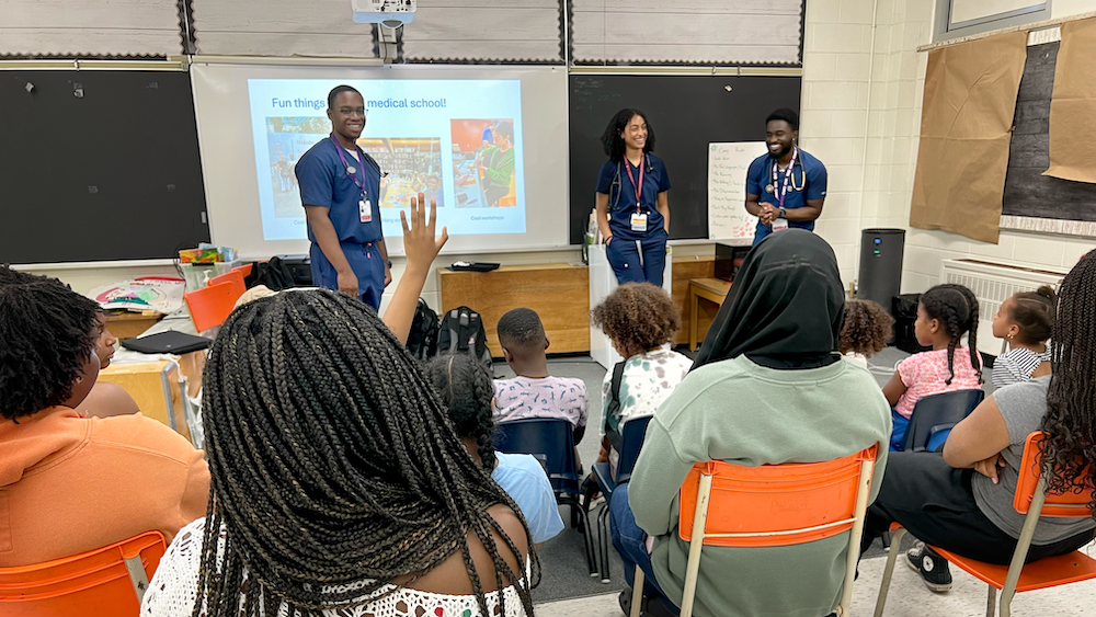 Three students giving a presentation to youth in a classroom
