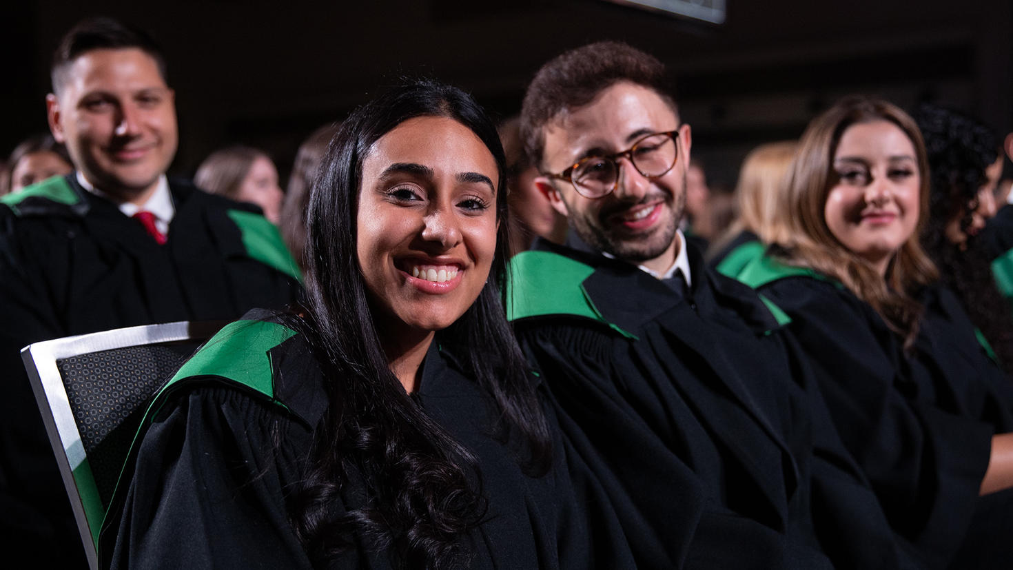 Two students sit in the audience at convocation.
