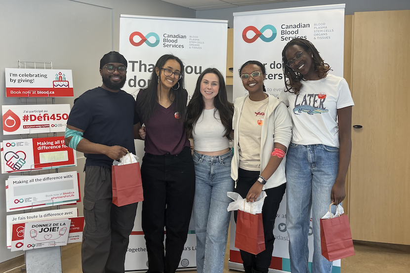 Five blood donors holding gift bags and smiling