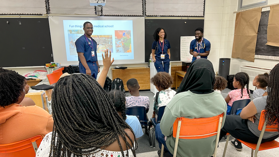 Three students giving a presentation to youth in a classroom