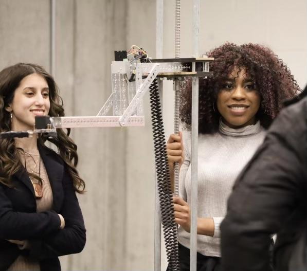 Laila and Lucy stand next to their machine