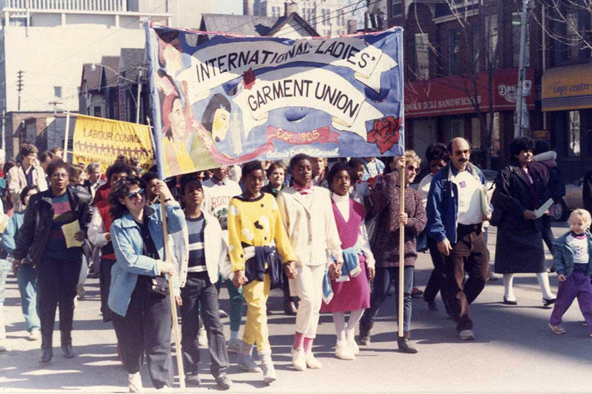 Participants carrying an “International Ladies' Garment Union” banner during an International Women's Day (IWD) demonstration in Toronto