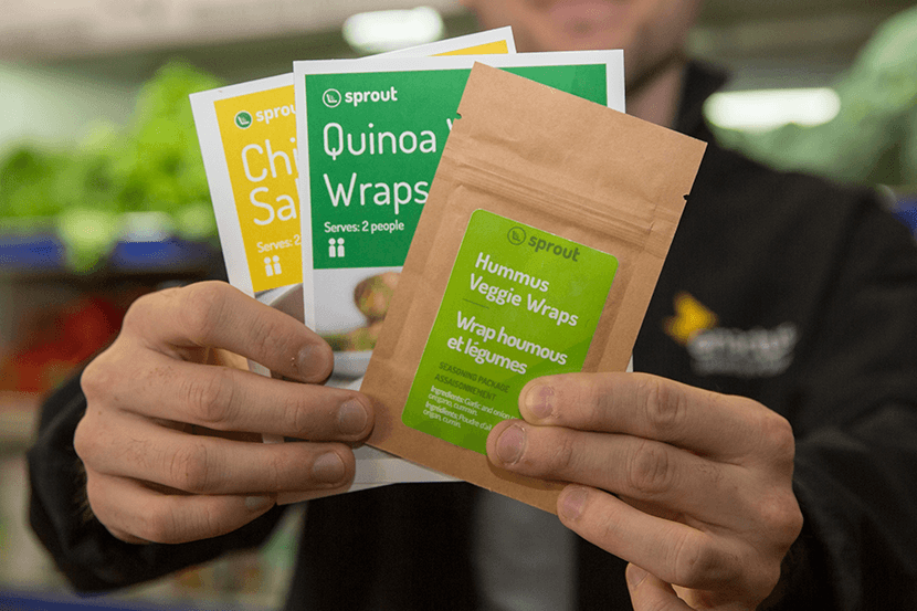 Close-up of a man’s hands holding two recipe cards and a packet of seasoning.