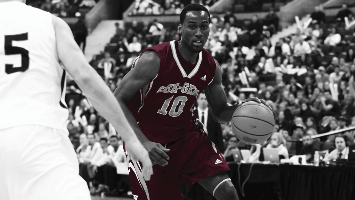 A Gee-Gees basketball player dribbling the ball around an opponent.
