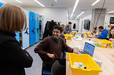Student in a maker lab smiling at professor.