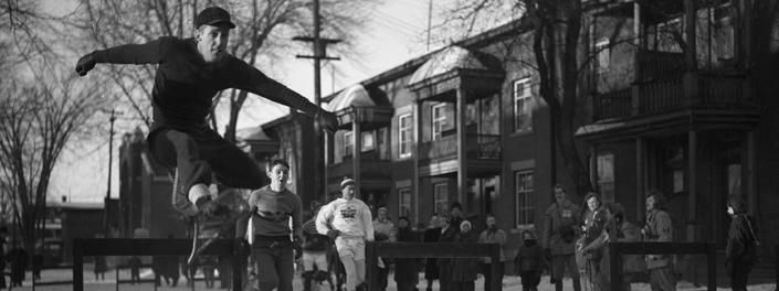 Young man wearing snowshoes jumping over an obstacle on a snow-covered King Edward Avenue.
