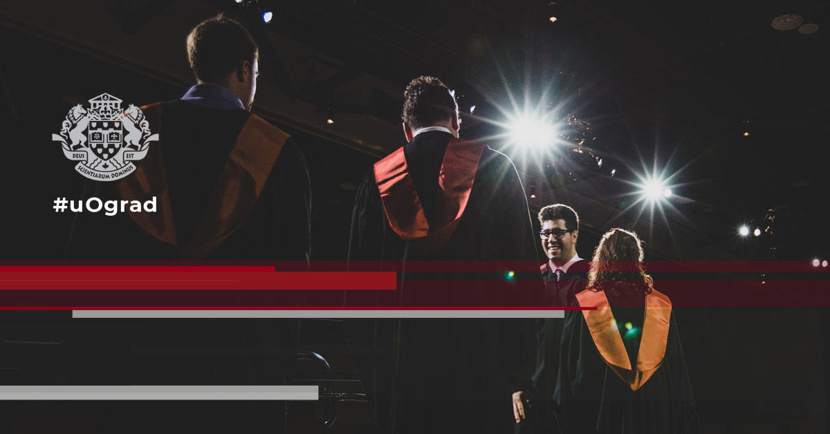 Graduating students in graduation gowns walk across the stage at convocation.